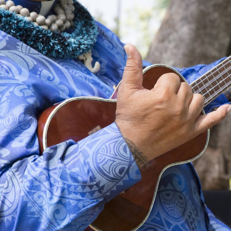 Oahu, Hawaii -- April 28, 2013: Native Hawaiian ukulele player practicing before wedding ceremony. Shows hang loose hand gesture.